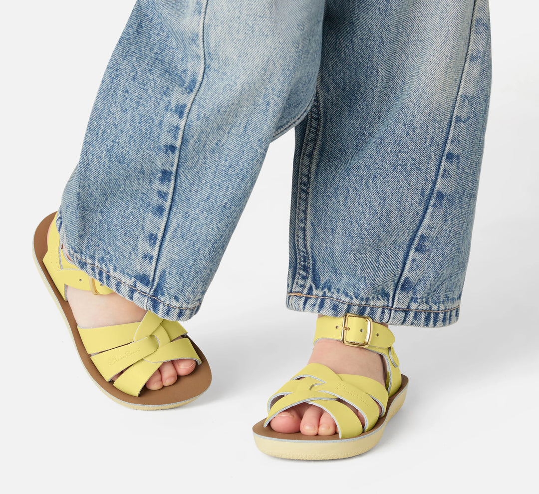 Kind met gele Salt Water sandalen in beweging, retro design met gevlochten bandjes