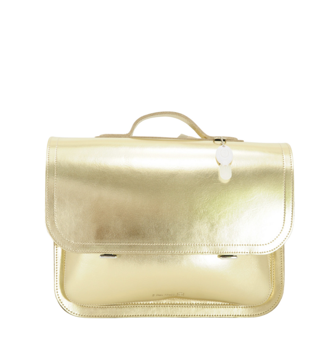 Gouden kinderrugzak met afgeronde flap en handvat bovenaan, voorzien van een witte labelhanger en metalen sluitingen, perfect als opvallende schooltas.