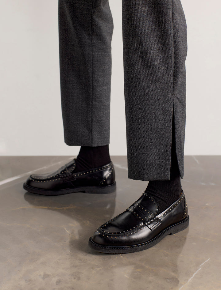 Dames draagt zwarte loafers met studs van Angulus – moderne en stijlvolle look