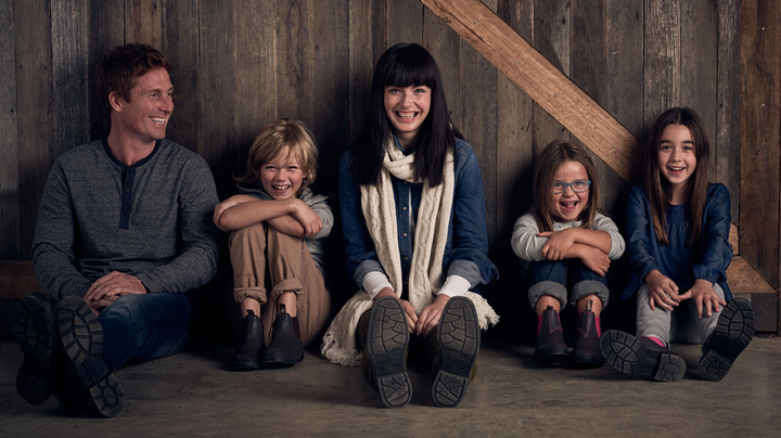 Gezin met kinderen draagt Blundstone Classic Clay 2446 laarzen, zittend tegen houten muur, casual kledingstijl