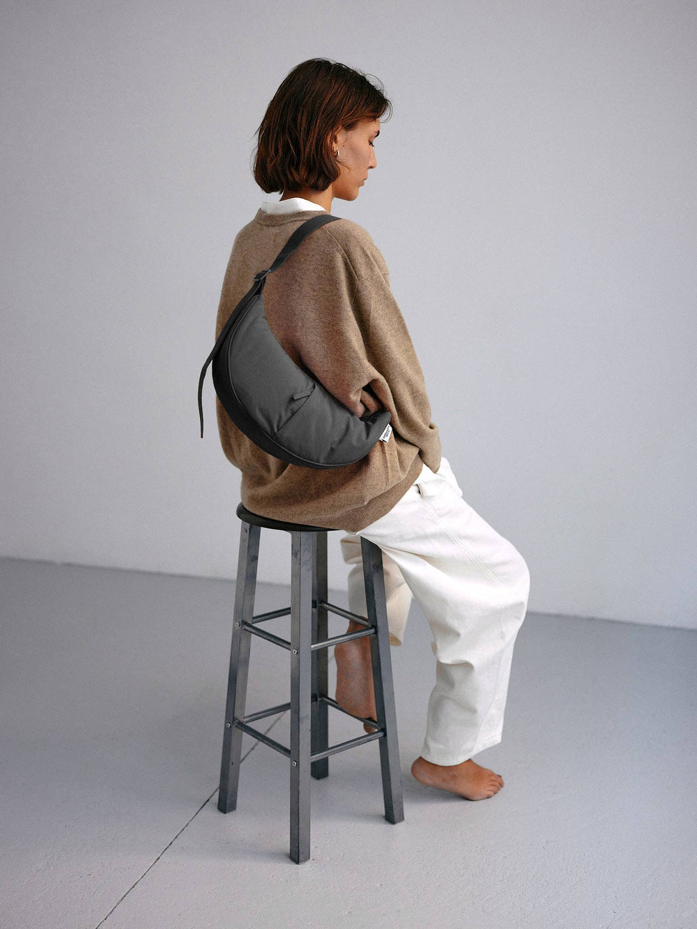 Vrouw met zwarte Mini Moon Bag crossbody gedragen – stijlvolle en comfortabele tas, perfect voor dagelijks gebruik