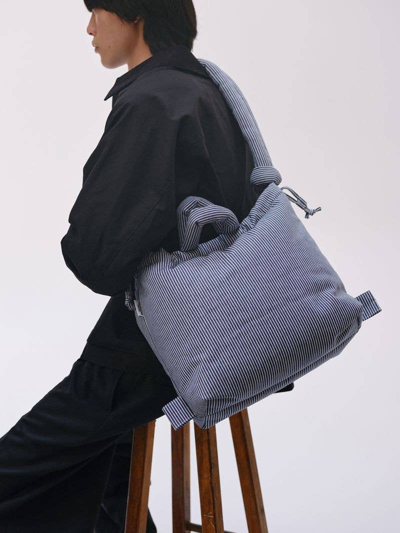Vrouw met blauw-wit gestreepte Ona-tas met gewatteerde knoopriemen – multifunctionele draagtas van Anna Pops